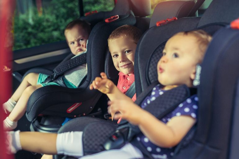 Three children in car safety seat - family, transport, safety
